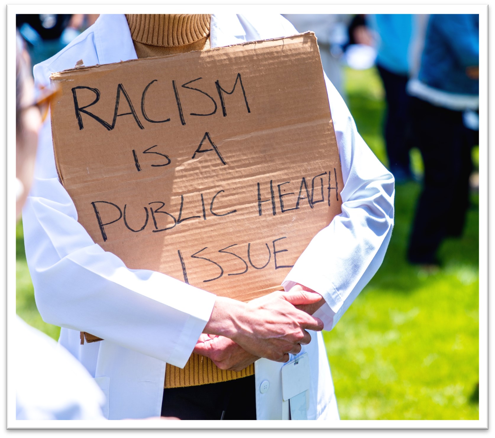 Person Carrying Racism is a Public Health Issue Sign